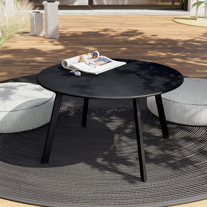 Round black outdoor table with magazines on a wooden deck
