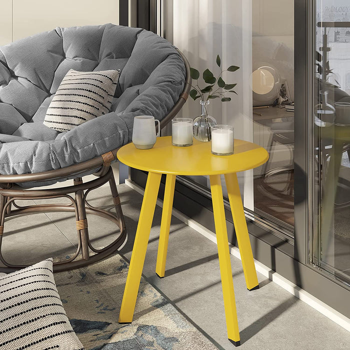 Yellow side table with candles next to a gray cushioned chair in a modern living room.