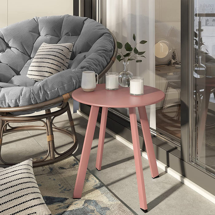 Pink side table with candles next to a gray cushioned chair in a modern living room.