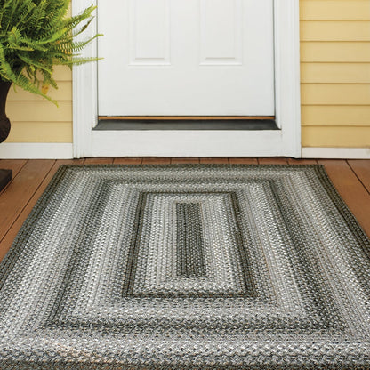 Textured outdoor rug on a wooden deck with a white door and yellow wall in the background.