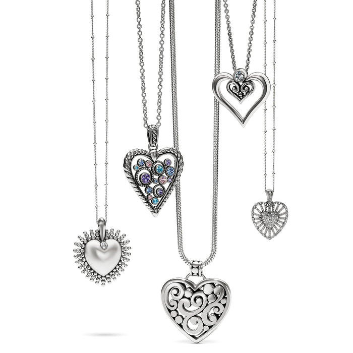 Brighton silver-plated heart pendant necklaces displayed together with crystal accents and openwork scroll designs on a white background