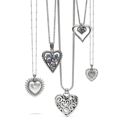 Brighton silver-plated heart pendant necklaces displayed together with crystal accents and openwork scroll designs on a white background