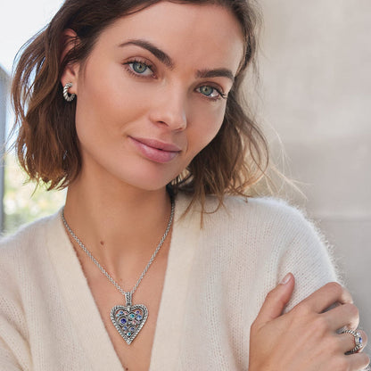 Model wearing a Brighton silver-plated heart pendant necklace with multicolored crystals paired with matching twisted hoop earrings