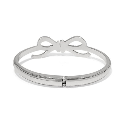 Brighton silver-plated bangle bracelet with bow accent and hinged opening shown from the back on a white background