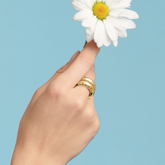 Model wearing a Brighton gold-tone ring with scroll cutout detail, holding a white daisy flower