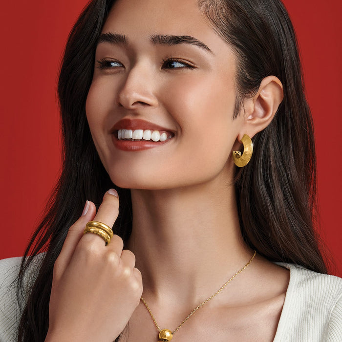 Model wearing Brighton gold-tone hoop earrings with coordinating Brighton stacked rings and pendant necklace accessories