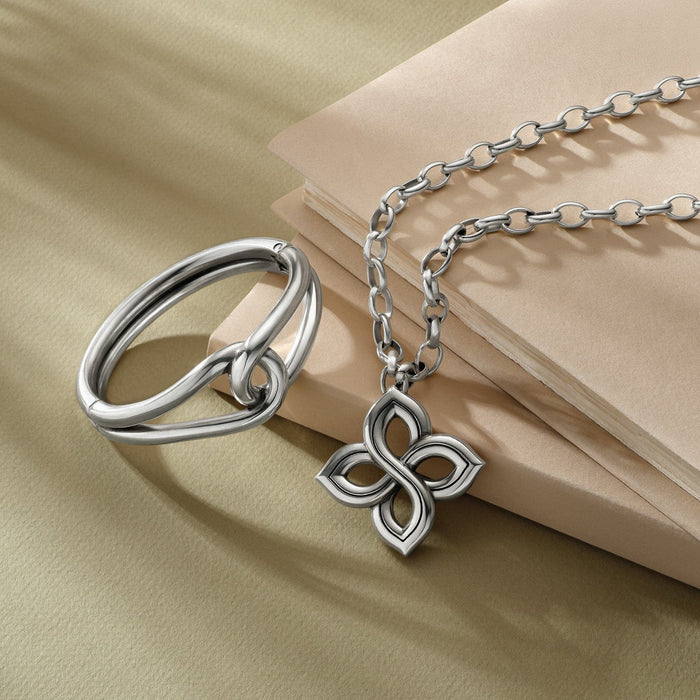 Brighton silver-plated ring and floral pendant necklace styled with stacked notebooks on a neutral background