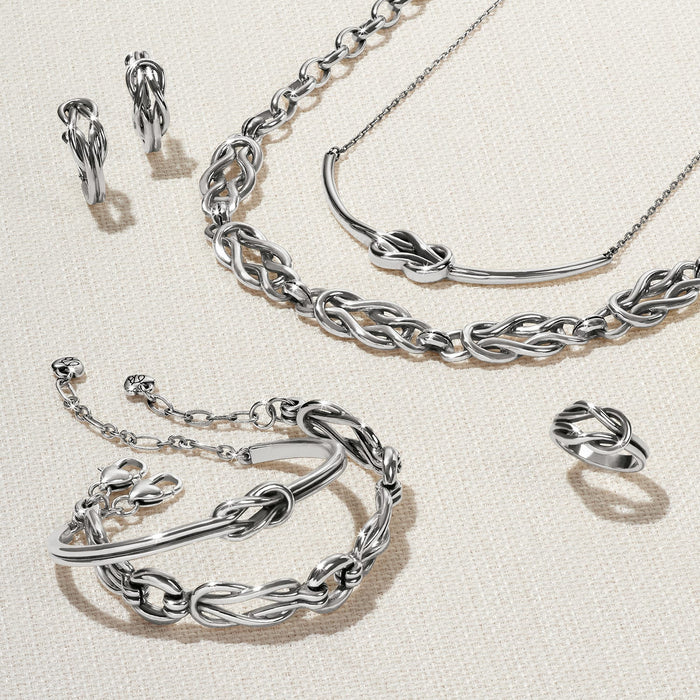 Brighton silver-plated jewelry set styled with knotted bracelets, hoop earrings, ring, and necklace on a neutral background