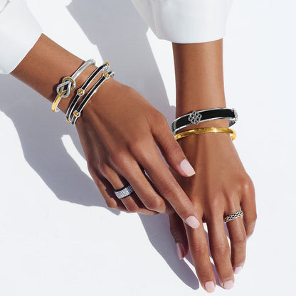 Model wearing Brighton silver-plated bangle bracelets with black enamel and gold accents and coordinating Brighton accessories