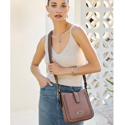 Model with a Brighton mauve leather crossbody handbag featuring whipstitch trim and braided strap, styled with coordinating Brighton accessories
