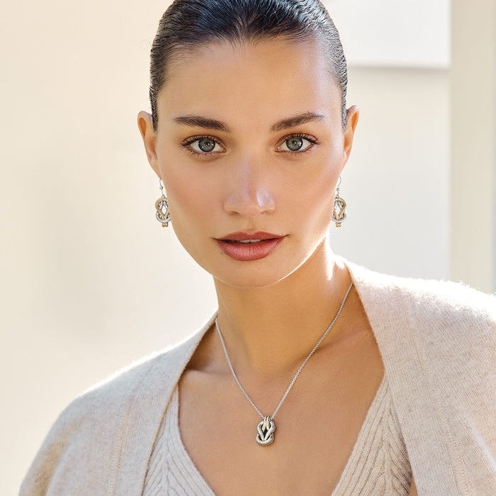 Model wearing a Brighton two-tone pendant necklace with woven knot design paired with matching drop earrings
