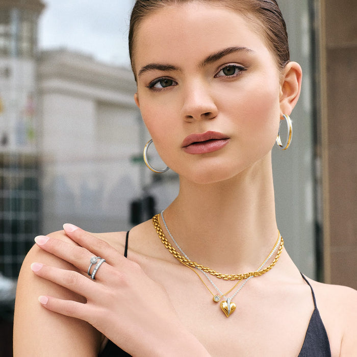 Model wearing Brighton two-tone hoop earrings with layered gold link necklaces and coordinating Brighton accessories