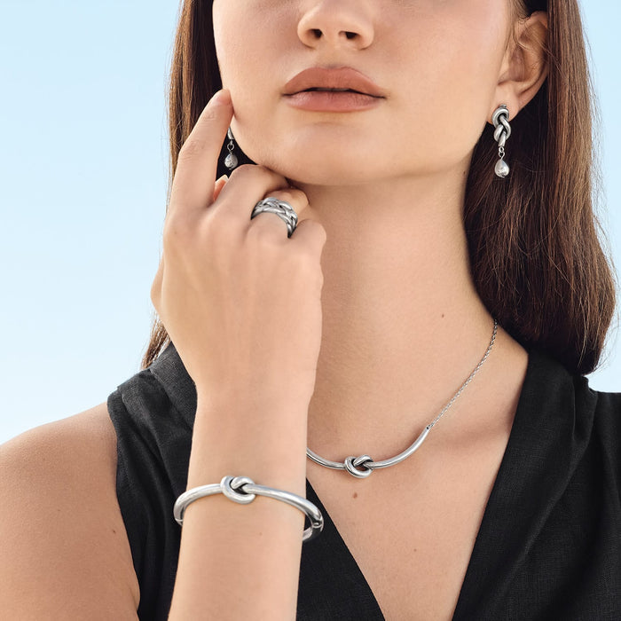 Model wearing a Brighton silver knot necklace with coordinating Brighton knot earrings, bracelet, and woven ring