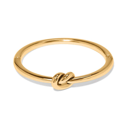 Brighton gold-plated bangle bracelet with polished knot accent at the front on a white background
