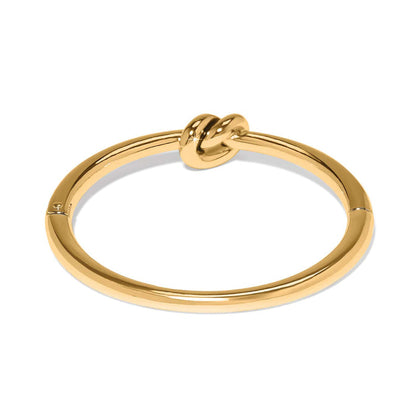 Brighton gold-plated bangle bracelet with sculpted knot design at the center on a white background