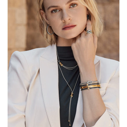 Model wearing Brighton two-tone hoop earrings with matching knot ring, layered necklaces, and stacked bangle bracelets