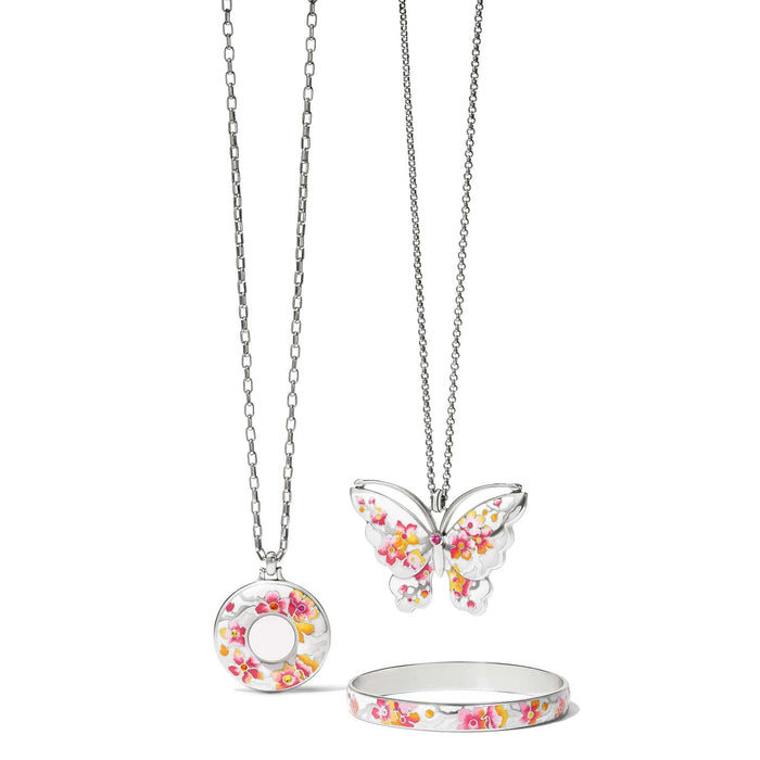 Brighton silver-plated jewelry set with butterfly pendant, round locket necklace, and floral enamel bangle on a white background