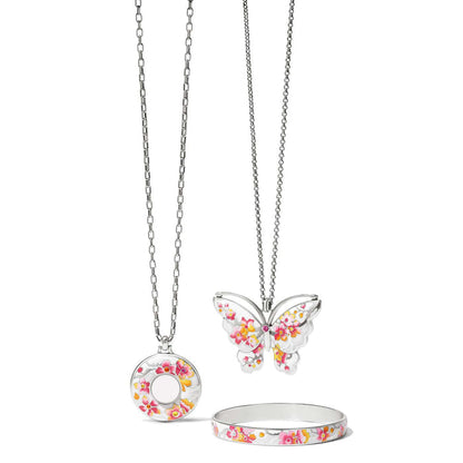 Brighton silver-plated jewelry set with butterfly pendant, round locket necklace, and floral enamel bangle on a white background