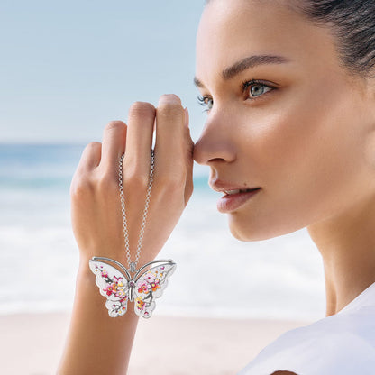 Model holding a Brighton silver-plated butterfly pendant necklace with pink enamel floral wing details and crystal accent