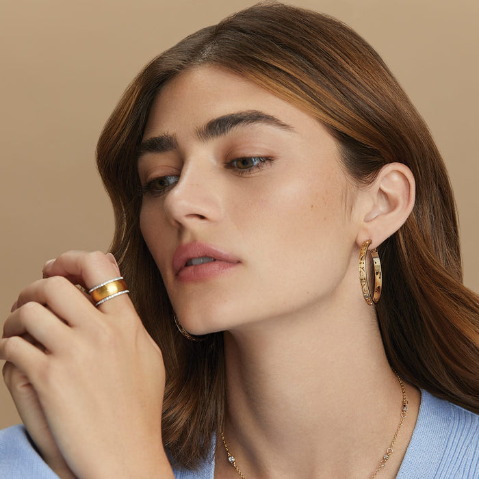 Model wearing a Brighton gold-plated hoop earring with scroll detail and coordinating Brighton crystal rings