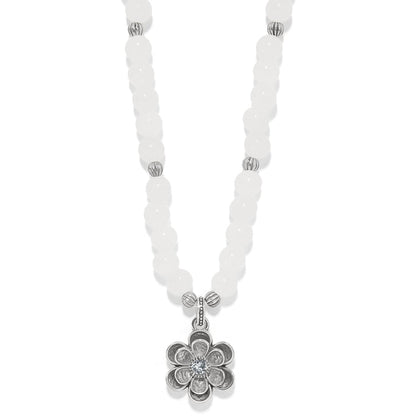 Brighton beaded necklace with white dyed jade beads and silver-plated flower pendant with crystal center on a white background