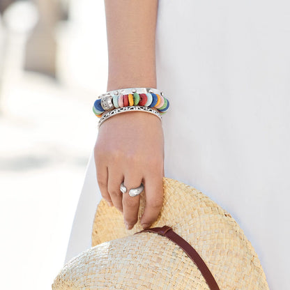 Model wearing a Brighton beaded bracelet with colorful Ashanti beads and silver-plated cuff, holding a straw hat