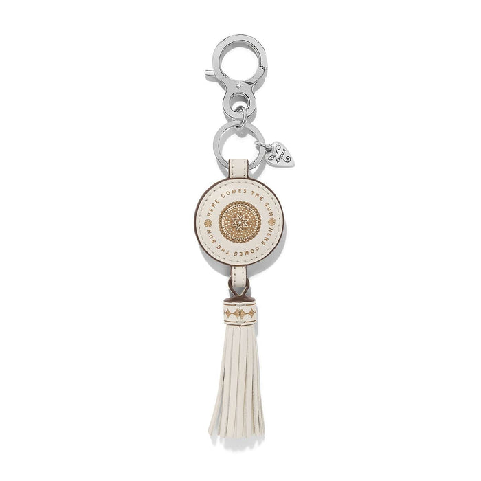 Brighton leather key fob with cream medallion, Here Comes the Sun text, tassel, and silver-tone clasp on a white background