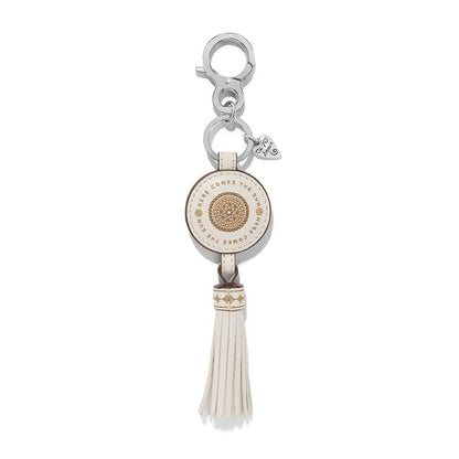 Brighton leather key fob with cream medallion, Here Comes the Sun text, tassel, and silver-tone clasp on a white background