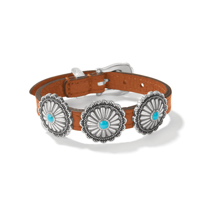 Brighton bracelet with brown leather strap, three silver-plated concho medallions, turquoise stones, and buckle closure on a white background
