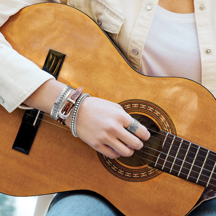 Model wearing stacked Brighton silver-plated bangles with engraved patterns, beaded design, and tooled leather buckle strap