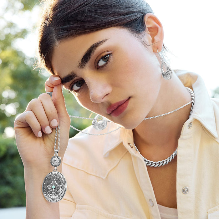 Model wearing a Brighton silver-plated oval pendant necklace with turquoise center and coordinating Brighton accessories