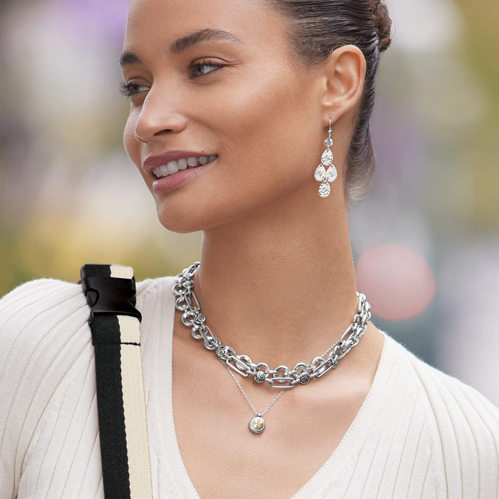 Model wearing Brighton silver-tone chandelier earrings with hammered discs and coordinating Brighton layered chain necklaces