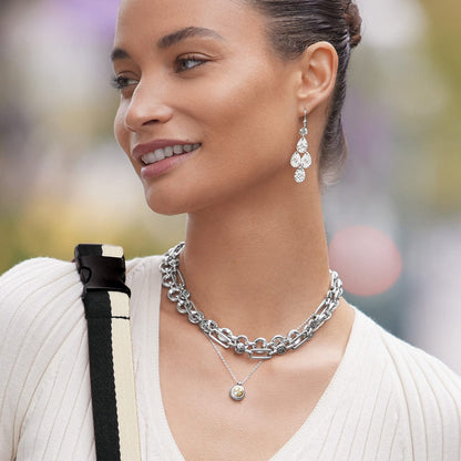 Model wearing Brighton silver-tone chandelier earrings with hammered discs and coordinating Brighton layered chain necklaces