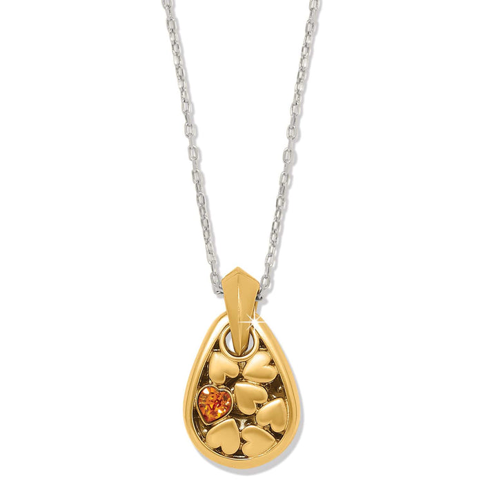 Brighton pendant necklace with gold-tone teardrop, heart details, orange crystal accent, and silver-tone chain on a white background