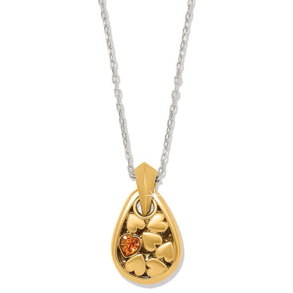 Brighton pendant necklace with gold-tone teardrop, heart details, orange crystal accent, and silver-tone chain on a white background