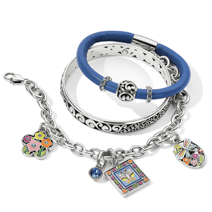 Brighton silver-plated bracelets styled with blue leather bangle and enamel floral butterfly charms on white background
