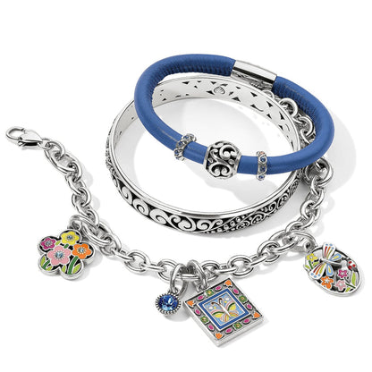 Brighton silver-plated bracelets styled with blue leather bangle and enamel floral butterfly charms on white background