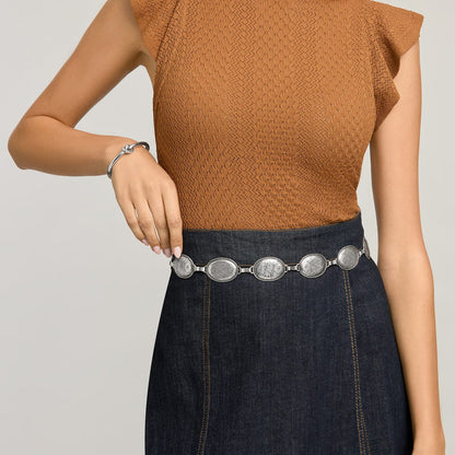 Model wearing a Brighton silver-tone concho belt with engraved oval medallions over a denim skirt