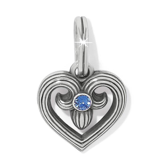 Brighton heart charm with scrolled silver-plated design and blue crystal center on a white background