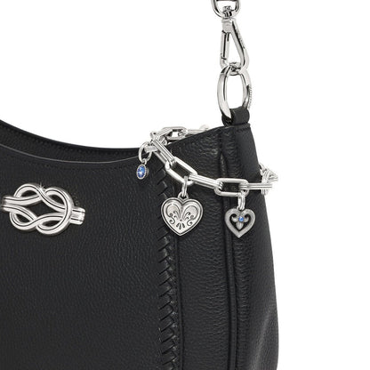 Close-up of Brighton black leather handbag with silver-plated chain strap, heart charms, and blue crystal accents