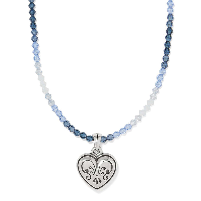 Brighton pendant necklace with blue beads and silver-plated engraved heart charm on a white background