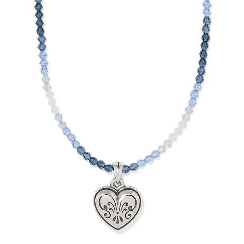 Brighton pendant necklace with blue beads and silver-plated engraved heart charm on a white background