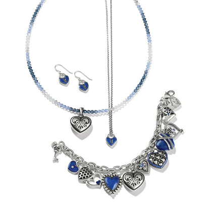 Brighton silver-plated heart jewelry styled with blue beaded necklace and charm bracelet on a white background