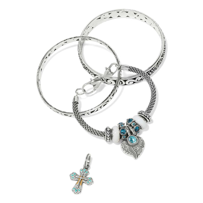 Brighton silver-plated bangle bracelets styled with a blue crystal charm bead set and cross charm on white