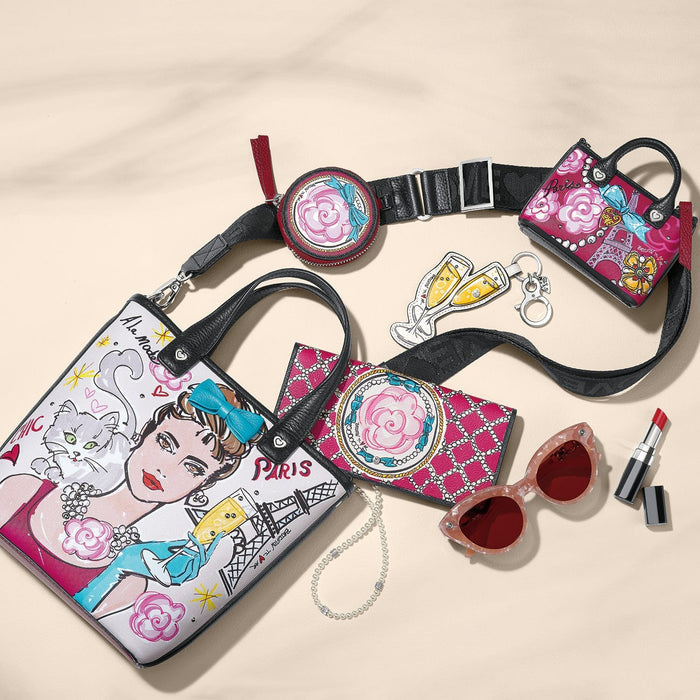 Brighton leather handbag with illustrated Paris print, styled with sunglasses and other accessories on a neutral background