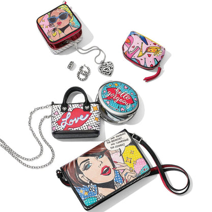 Brighton handbag collection styled with pop-art illustrated prints, silver heart pendant necklace, and other accessories on white background