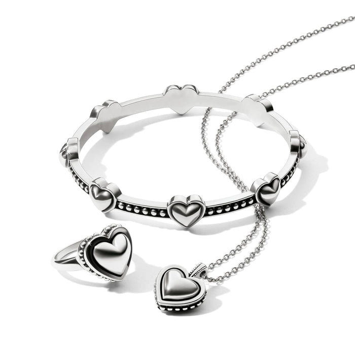 Brighton silver-plated heart bangle, heart ring, and heart pendant necklace styled together on a white background