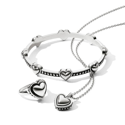 Brighton silver-plated heart bangle, heart ring, and heart pendant necklace styled together on a white background