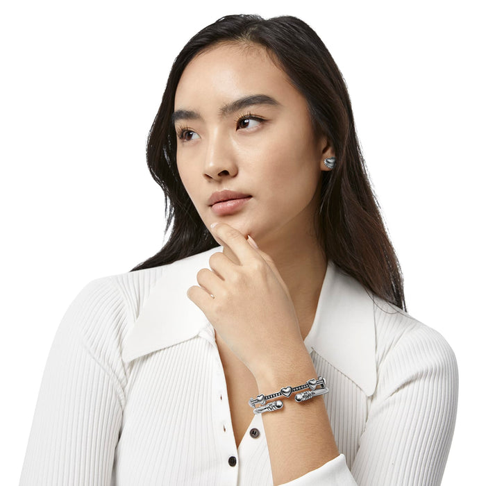 Model wearing a Brighton silver-plated bangle bracelet with heart stations and beaded accents, paired with matching heart stud earrings