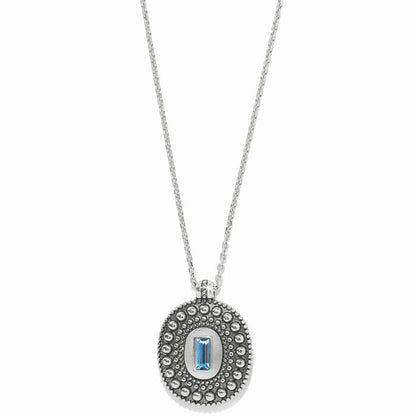 Brighton pendant necklace with silver-plated beaded oval medallion and blue crystal baguette center on a white background